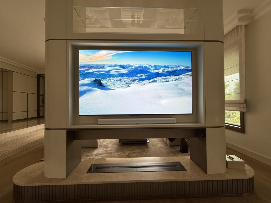 Cloison laquée avec écran et Sonos Arc dans la TV room d'une villa à Genève